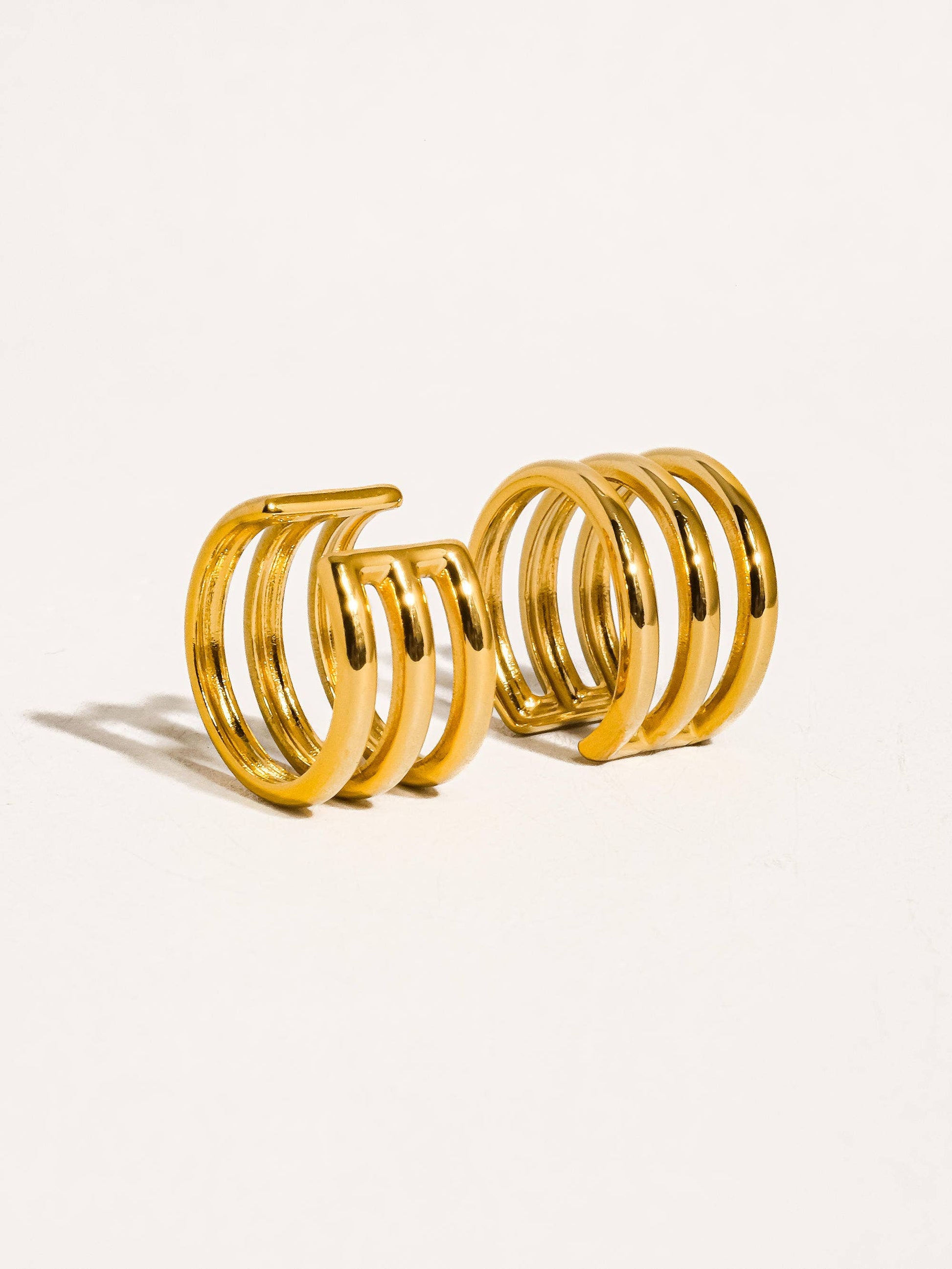 Pair of gold ear cuffs on a light beige background
