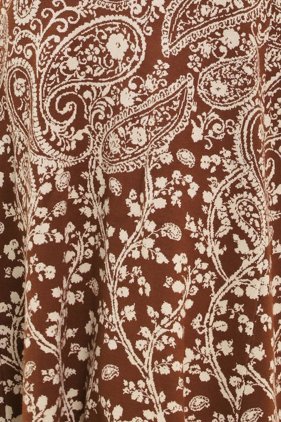 A close-up of a brown fabric with a cream paisley and floral vine pattern.