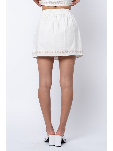 White skirt with lace trim worn by a person on a white background