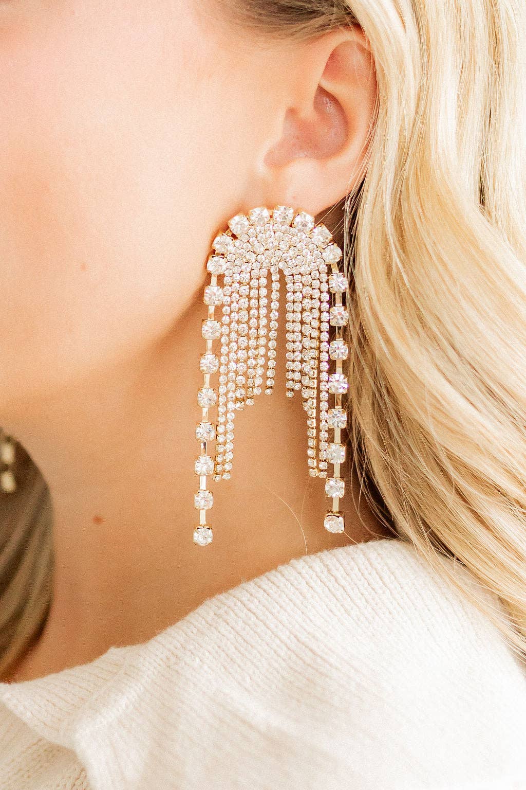 Close-up of a person wearing a sparkling earring with dangling beads.