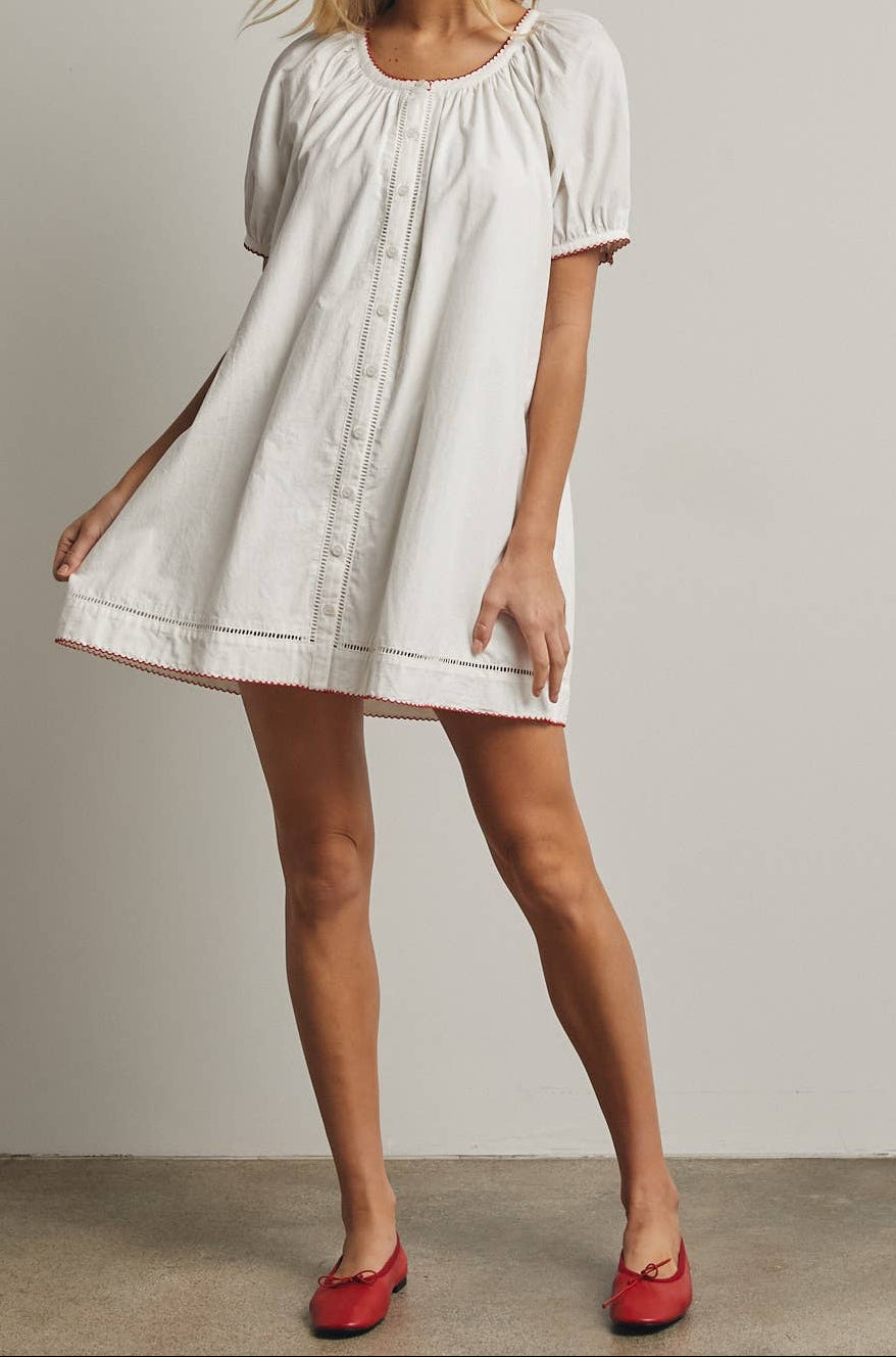 Woman wearing a white dress with short sleeves against a plain background