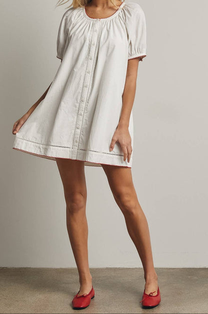 Woman wearing a white dress with short sleeves against a plain background