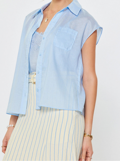 Woman wearing a light blue sleeveless shirt over a striped dress on a white background