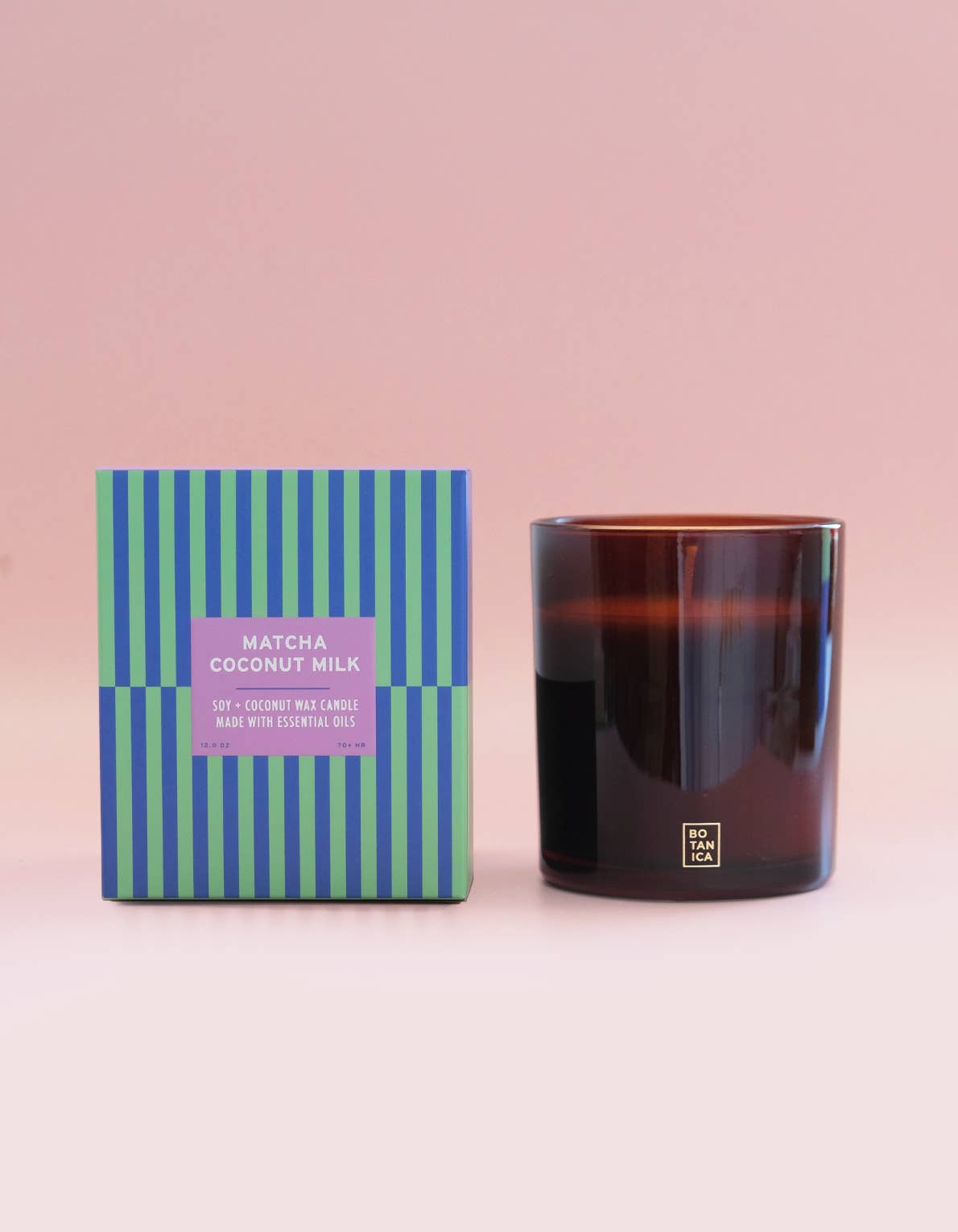 Candle and its packaging with a striped design on a pink background