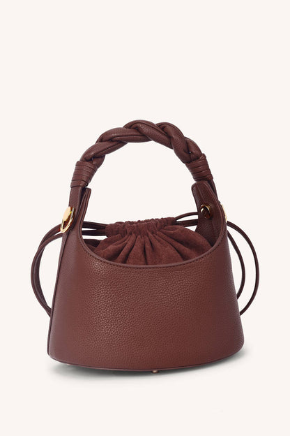 Brown leather handbag with braided handle on a white background