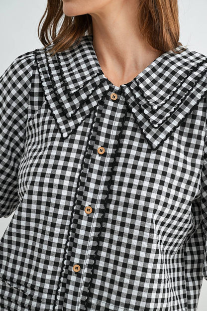 Black and white checkered shirt with wooden buttons on a plain background