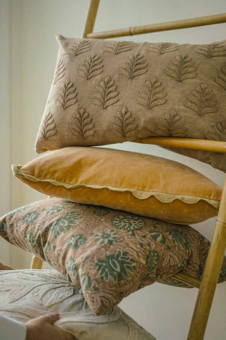 Stack of decorative pillows with leaf patterns on a chair