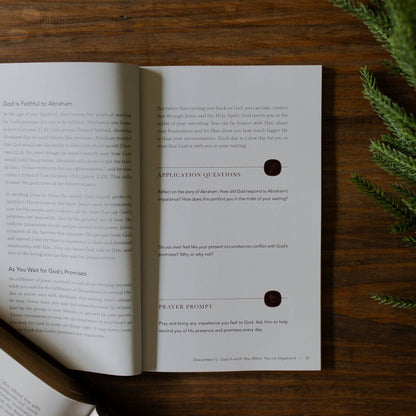 Open book with text and questions on a wooden surface with greenery