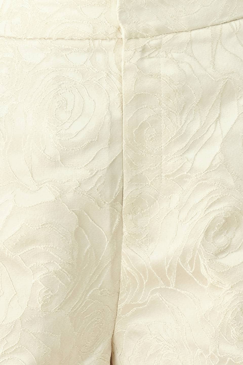 Close-up of a cream-colored fabric with a raised floral jacquard pattern and a central seam.