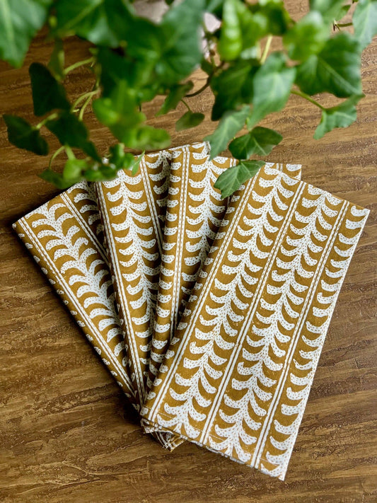 Set of patterned napkins on a wooden surface with greenery