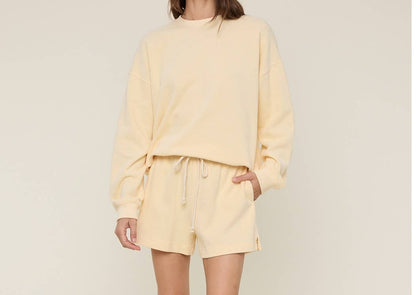 Person wearing a light yellow outfit with a blue hat on a beige background