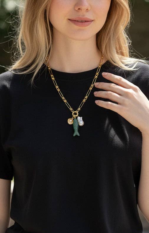 Person wearing a black shirt with a gold necklace featuring a fish pendant.