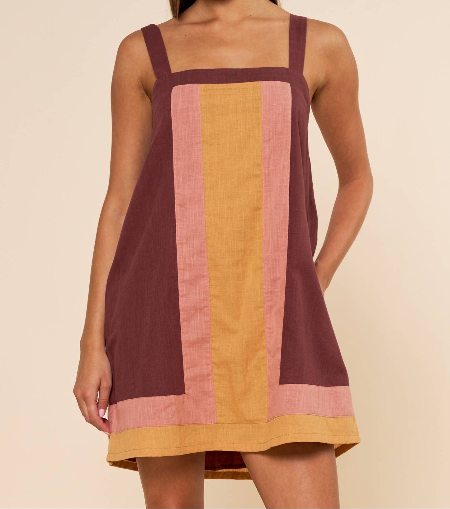 Woman wearing a sleeveless dress with vertical color stripes on a beige background
