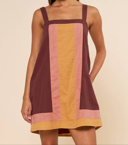 Woman wearing a sleeveless dress with vertical color stripes on a beige background