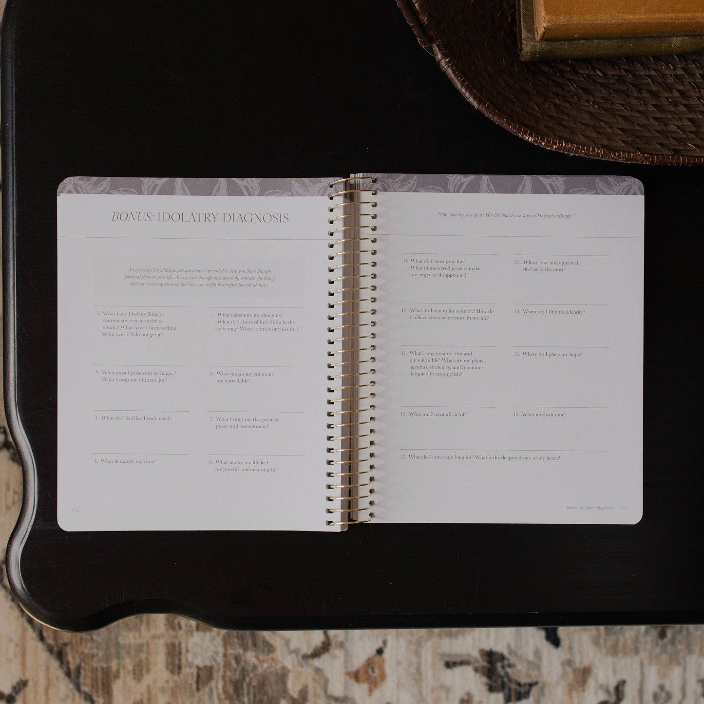 Open spiral-bound book on a dark surface with text and questions visible