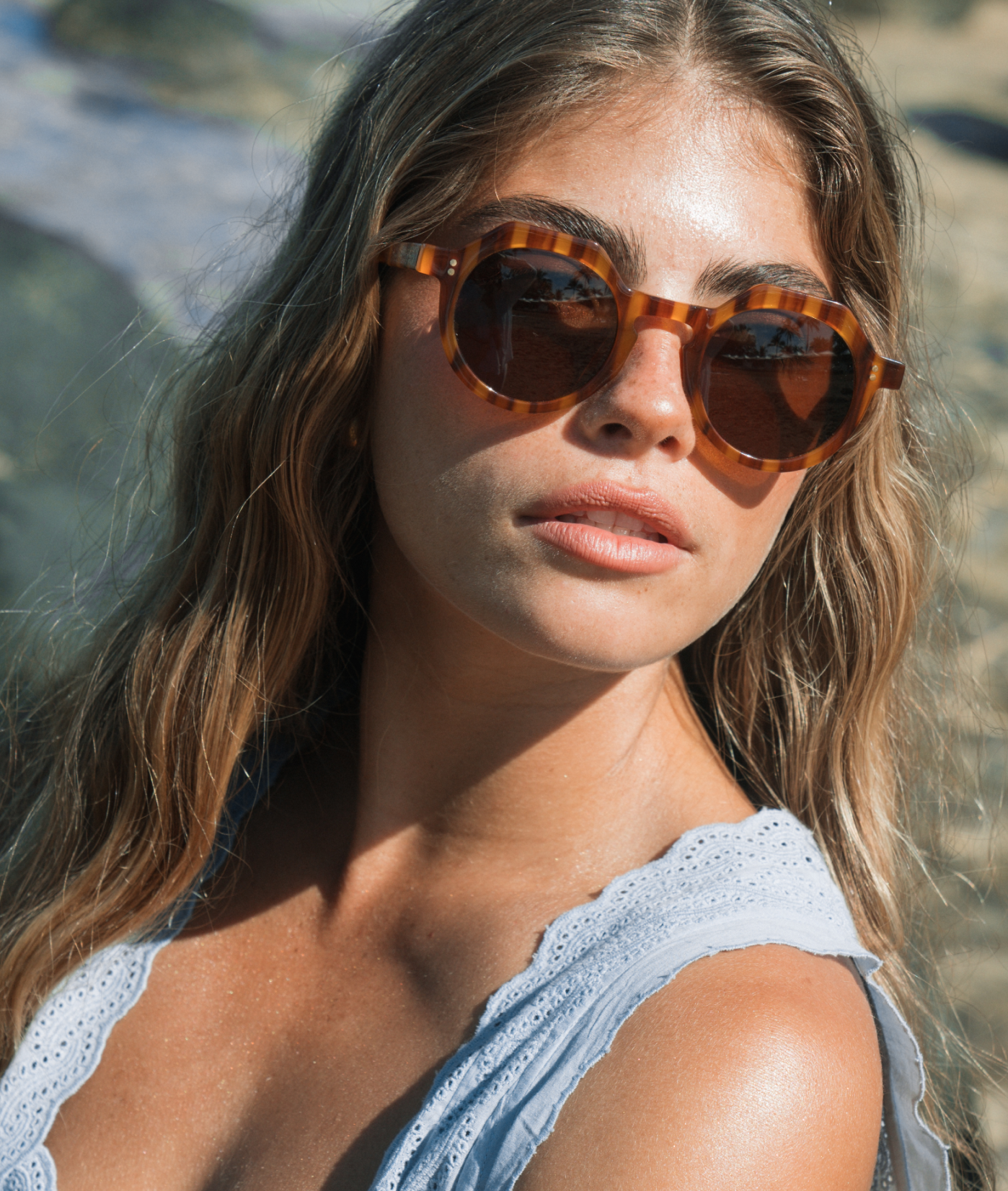 Woman wearing tortoiseshell sunglasses with a blurred natural background