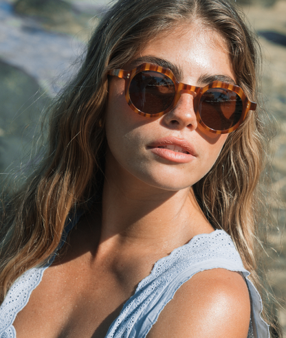Woman wearing tortoiseshell sunglasses with a blurred natural background