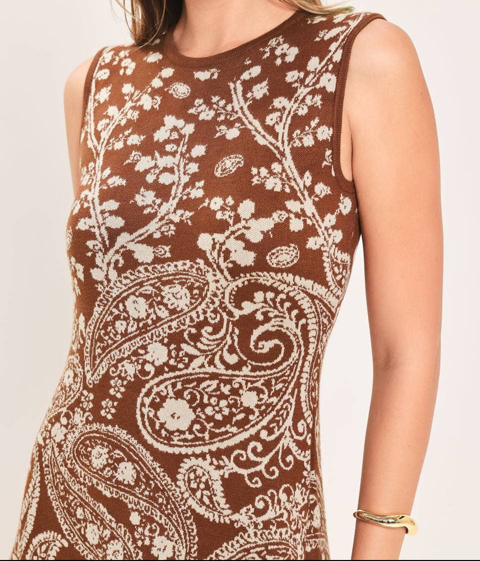 A woman wearing a sleeveless brown knit top with a cream paisley and floral pattern, shown against a plain light background.