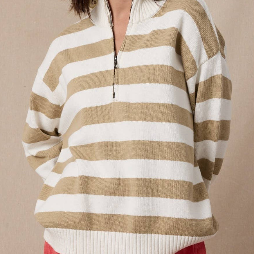 Woman wearing a beige and white striped sweater against a beige background
