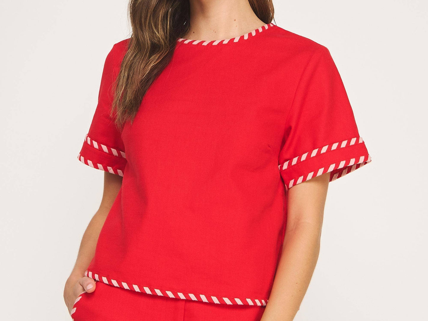 Woman wearing a red outfit with white trim on a plain background