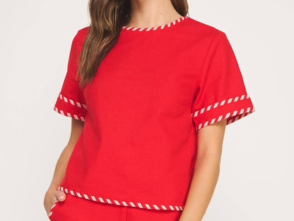 Woman wearing a red outfit with white trim on a plain background
