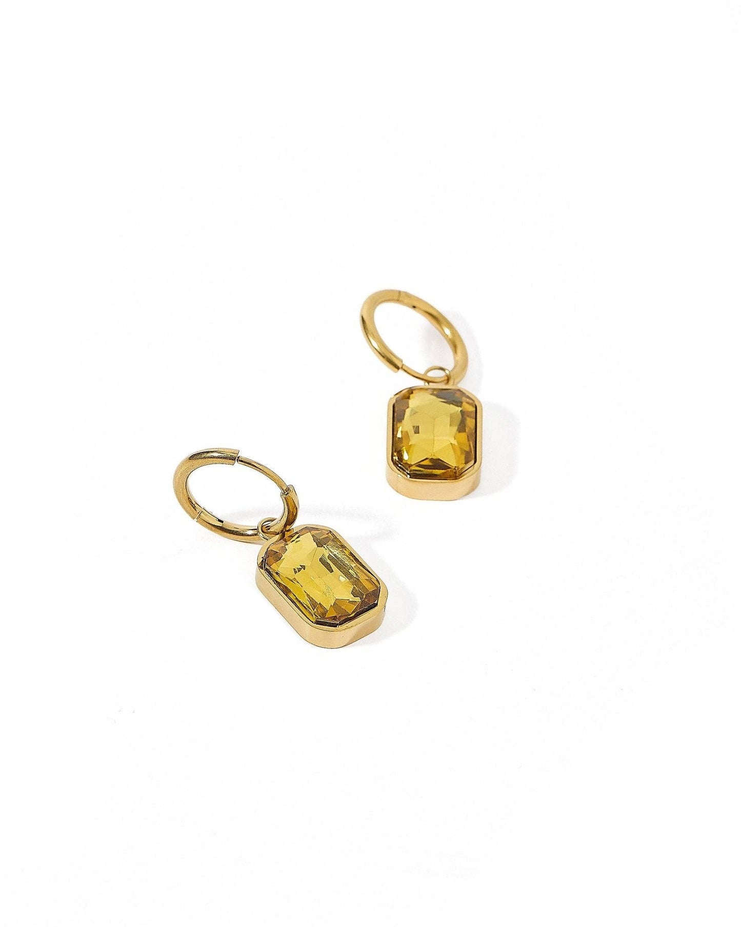 Gold earrings with yellow gemstones on a white background