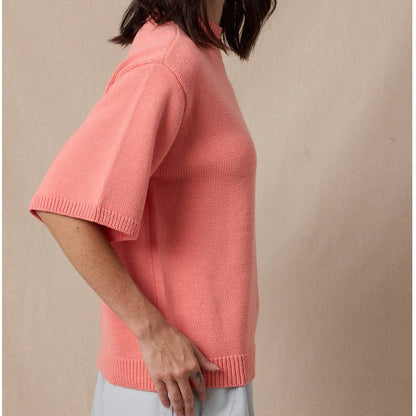 Woman wearing a pink sweater against a beige background
