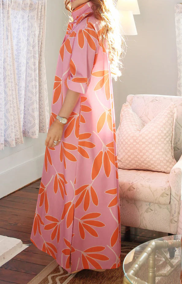 Woman in a pink dress with orange patterns standing in a living room.