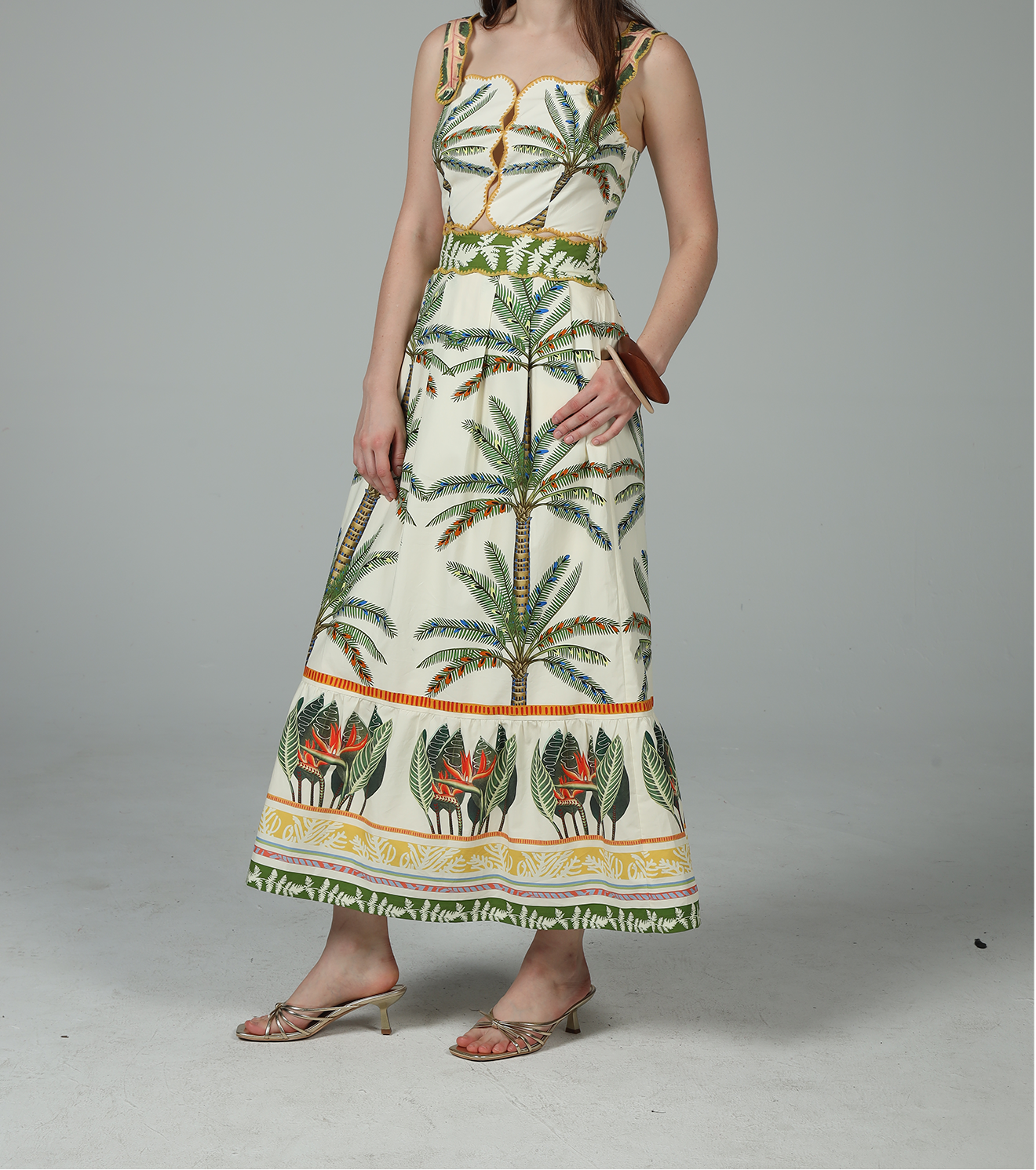 Woman wearing a long dress with palm tree pattern on a plain background