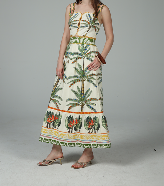 Woman wearing a long dress with palm tree pattern on a plain background