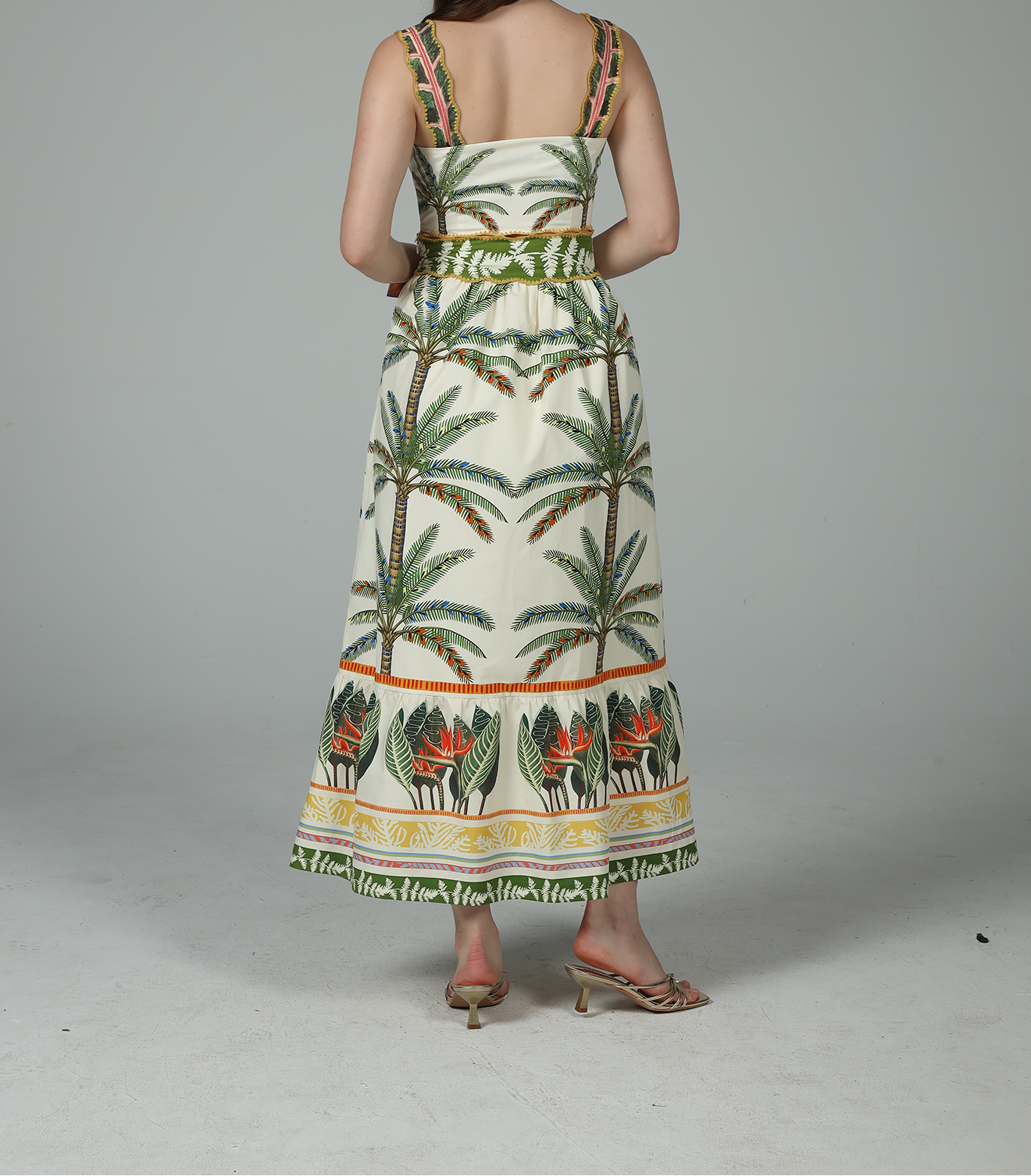 Woman wearing a palm tree patterned dress on a plain background
