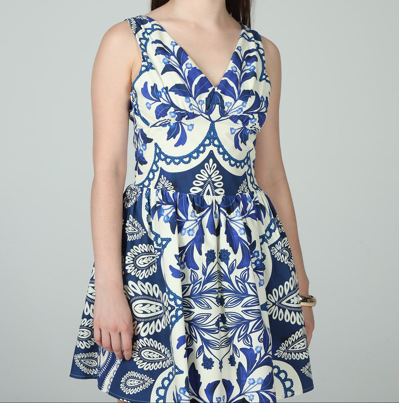 Woman wearing a blue and white patterned dress against a gray background