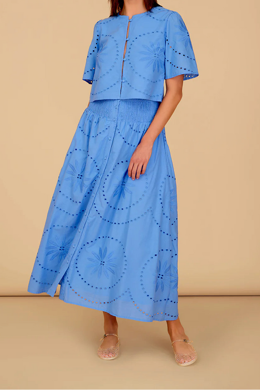 Woman wearing a blue outfit with circular patterns on a beige background