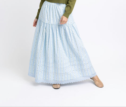 Woman wearing a green sweater and light blue plaid skirt on a white background