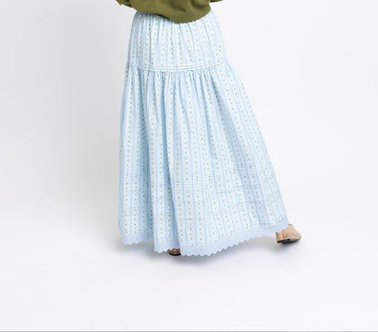 Person wearing a green sweater and light blue plaid skirt on a white background