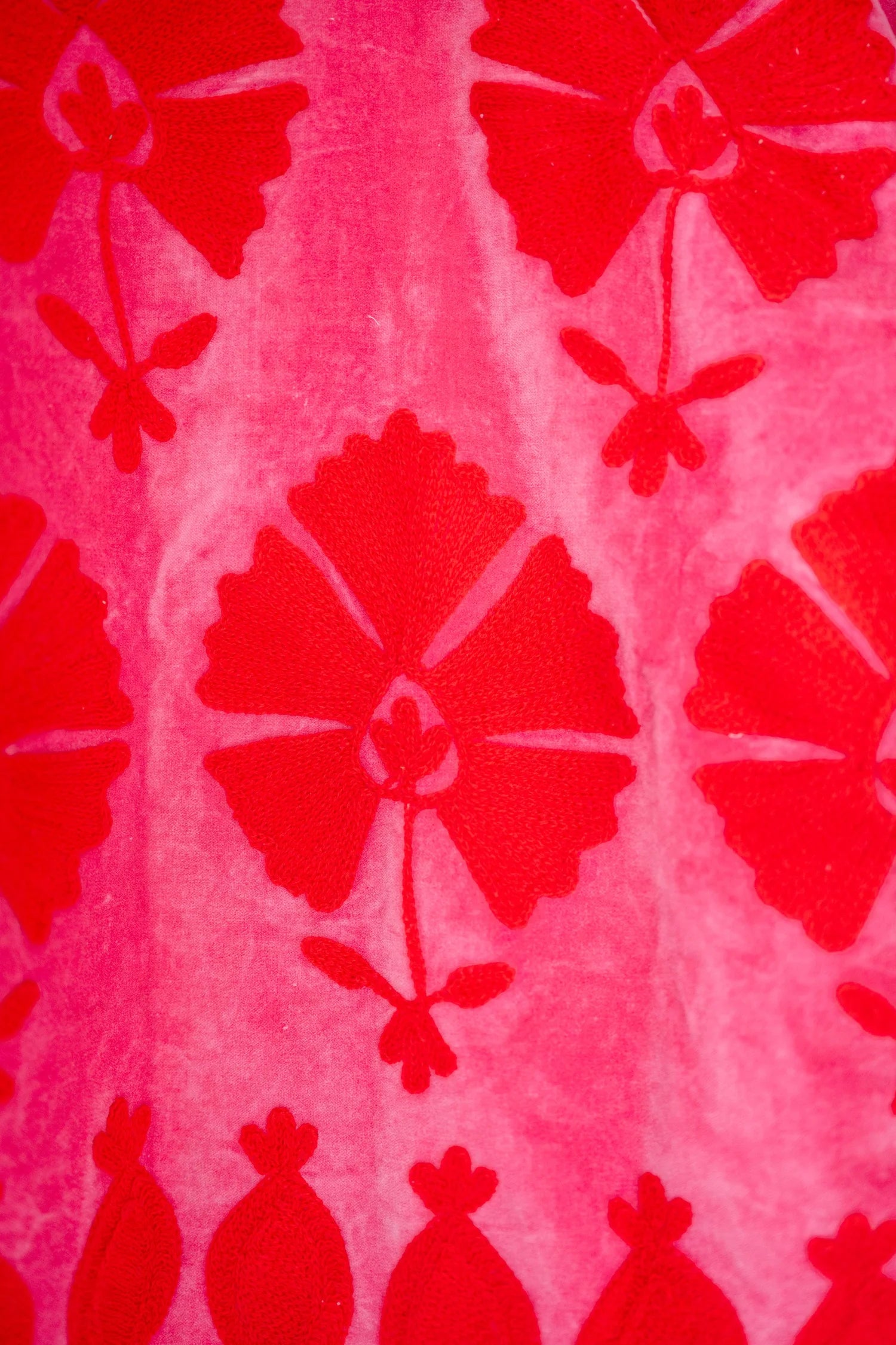 A close-up of a pink and red patterned fabric with a repeating floral motif.