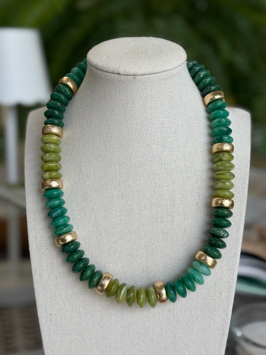 Green beaded necklace on a mannequin bust with a blurred background