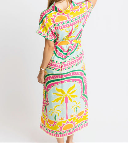 Woman wearing a colorful dress with a palm tree pattern on a white background