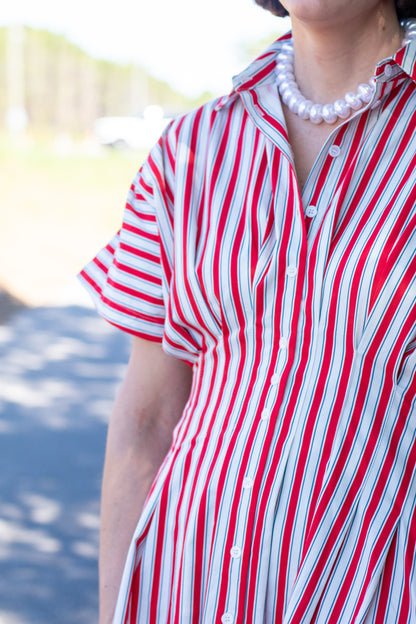 Person wearing a red and white striped shirt with a blurred outdoor background