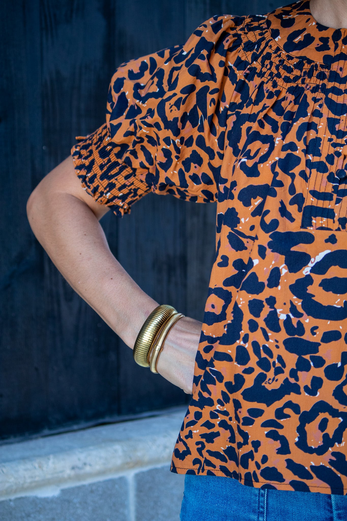 Person wearing an orange and black leopard print top with a blurred background