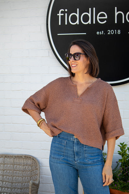 Woman wearing sunglasses and a brown top in front of a 'fiddle haus' sign.
