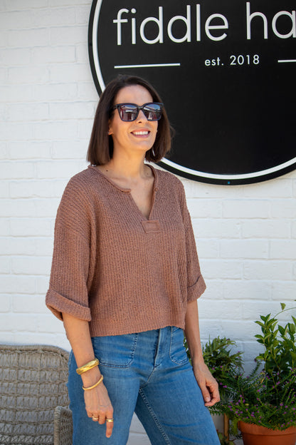 Woman wearing sunglasses and a brown top in front of a 'fiddle haus' sign.