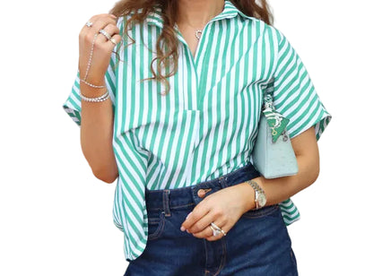 Person wearing a green and white striped shirt with blue jeans, standing outdoors.