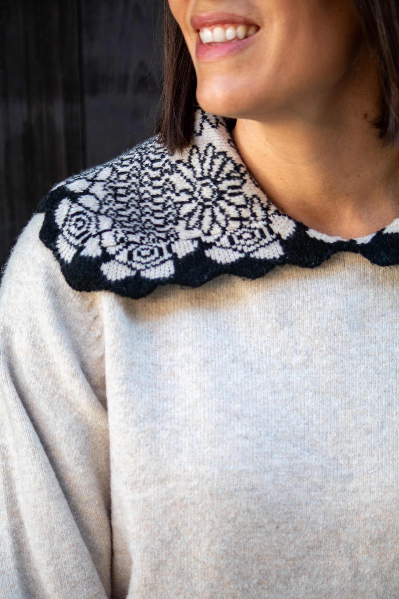 Person wearing a light-colored sweater with a black and white patterned collar.