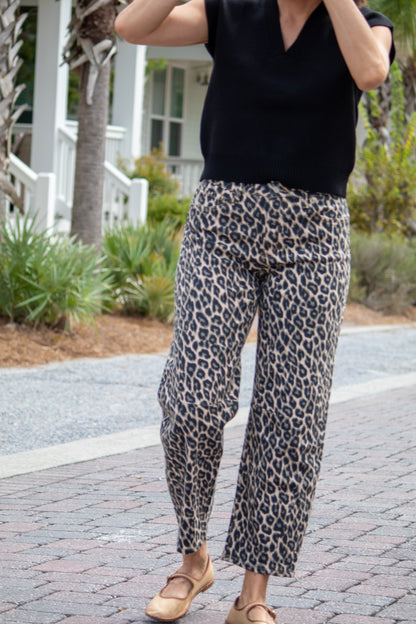 Person wearing a black top and leopard print pants outdoors.