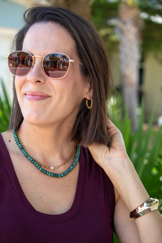 Woman wearing sunglasses and a necklace outdoors