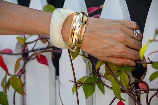 Close-up of a hand wearing gold bangles and a ring, with a blurred background