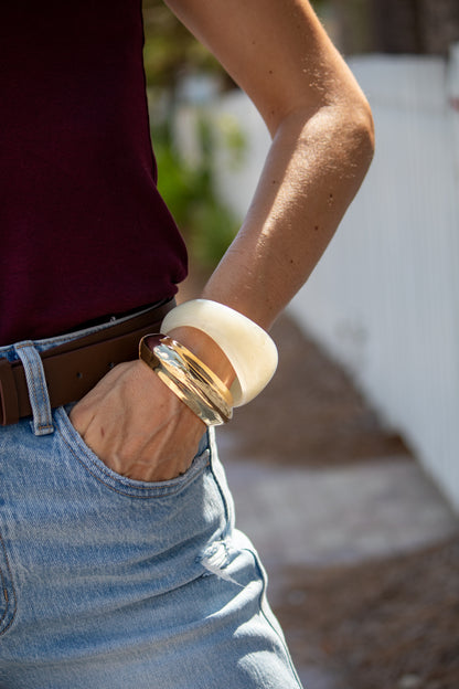 Person wearing a brown belt and light blue jeans with a blurred background