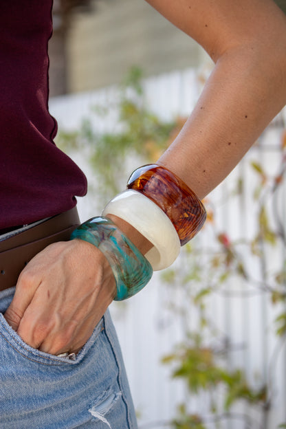 Close-up of a person's arm wearing colorful bracelets with a blurred background.