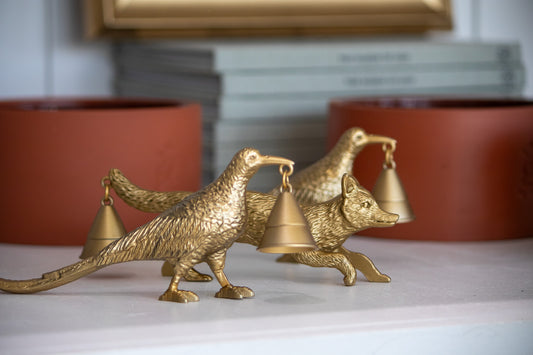 Gold animal-shaped candle snuffer on a white surface with blurred background